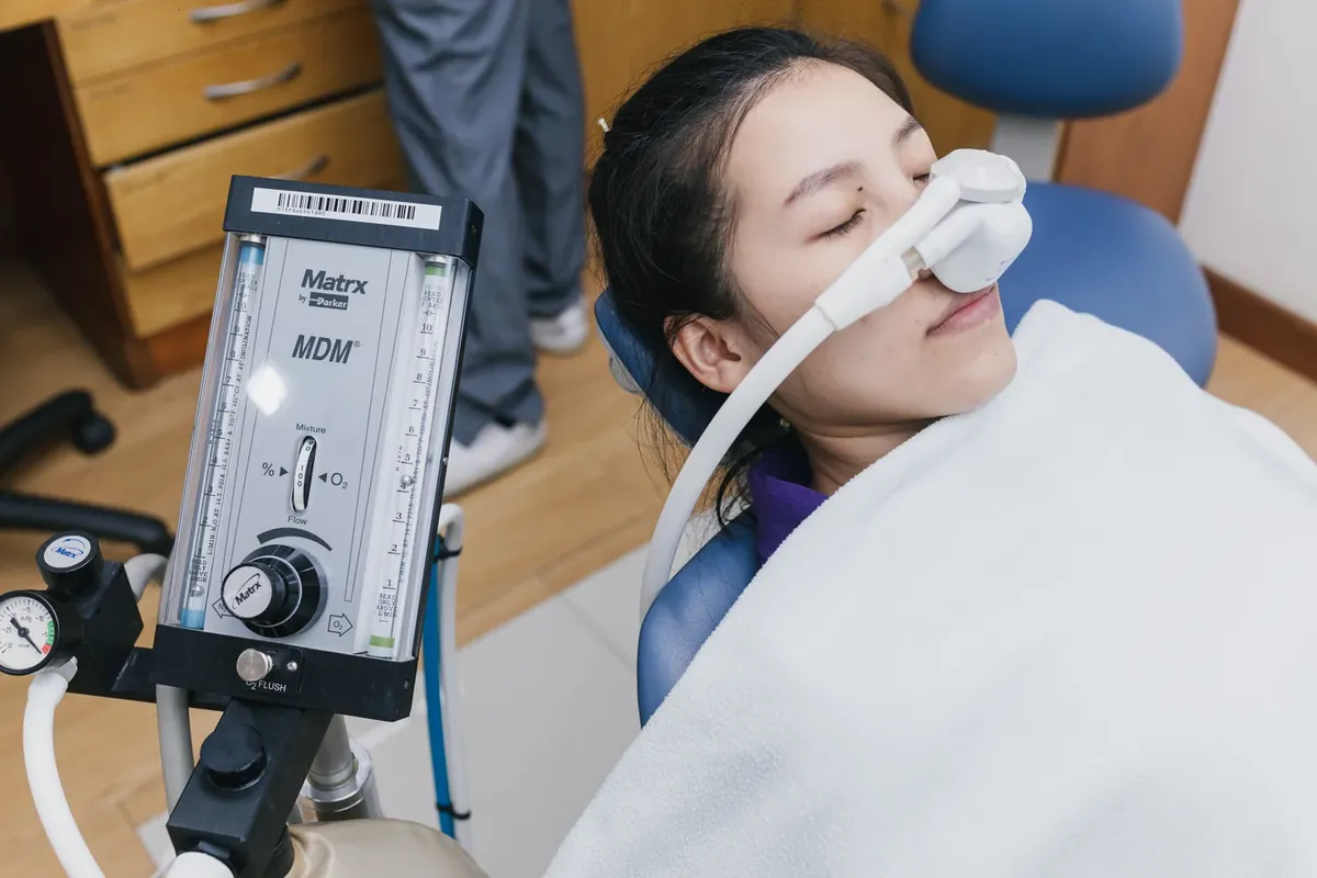 A relaxed patient breathing through a small nose mask for inhaled sedation