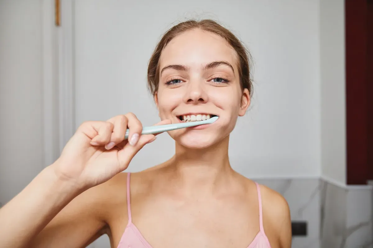 A smiling young woman brushing her teeth in the morning