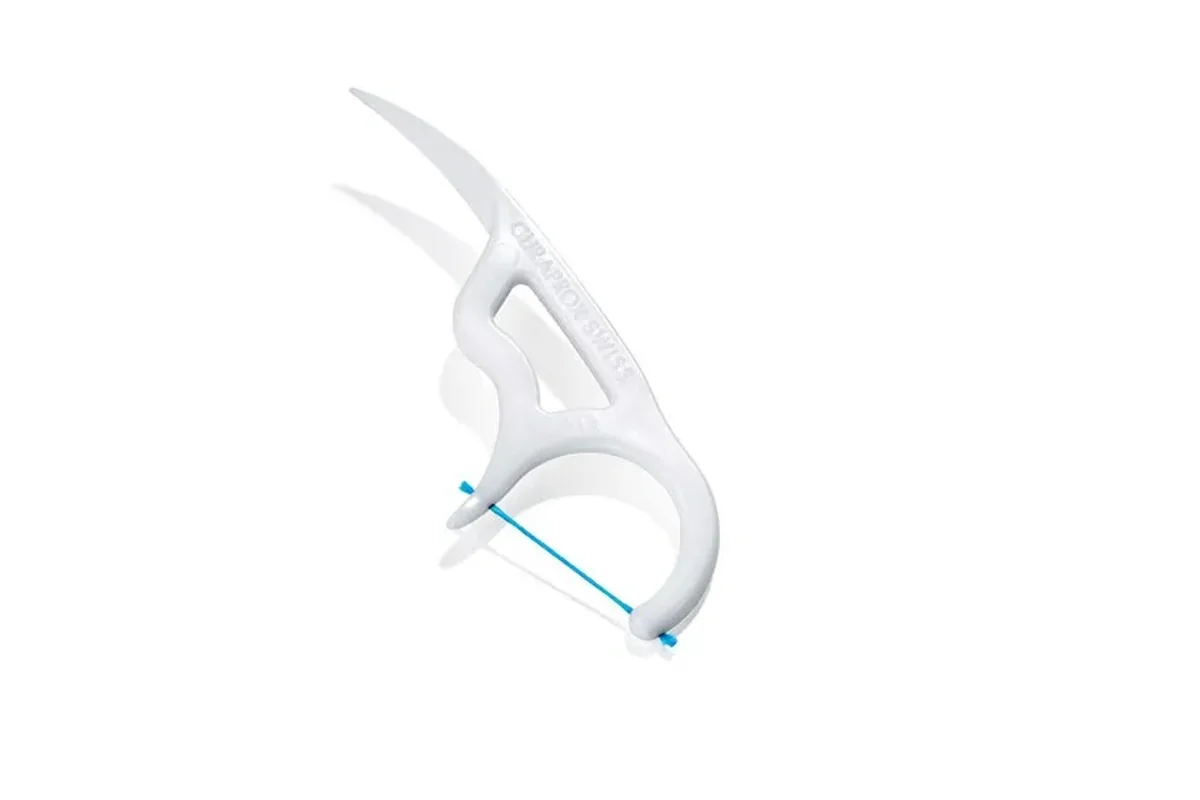 A white floss pick with a short piece of floss held between two prongs and a curved pointed handle