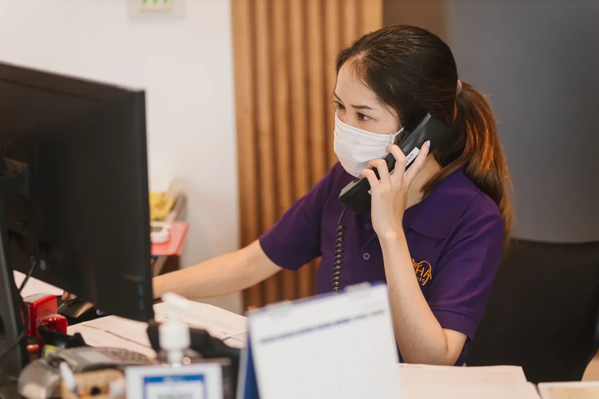 A receptionist talking on the phone at the front desk while booking an appointment