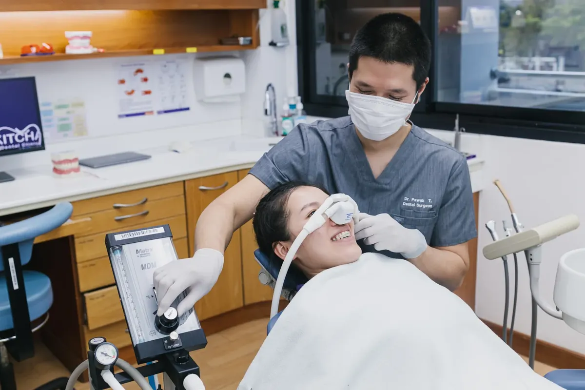 A dentist fitting an inhaled sedation nose mask for a relaxed patient