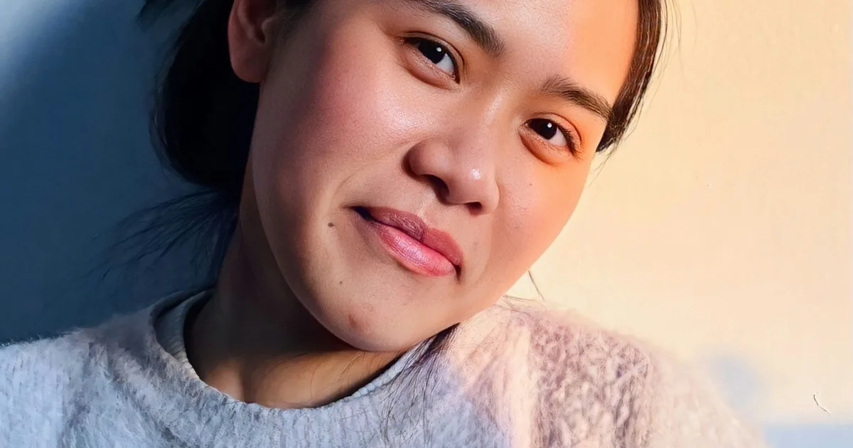 A young Asian woman smiling softly in warm evening light