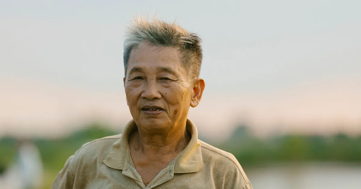A smiling senior Asian man outdoors in warm evening light