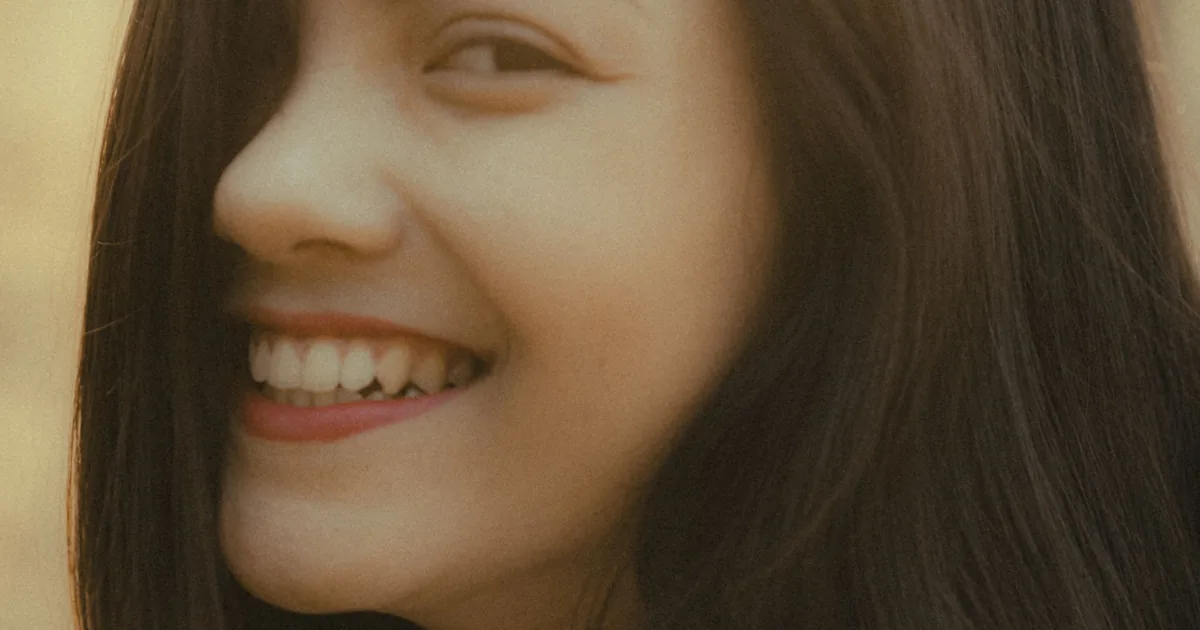 A young woman smiling warmly in soft golden light