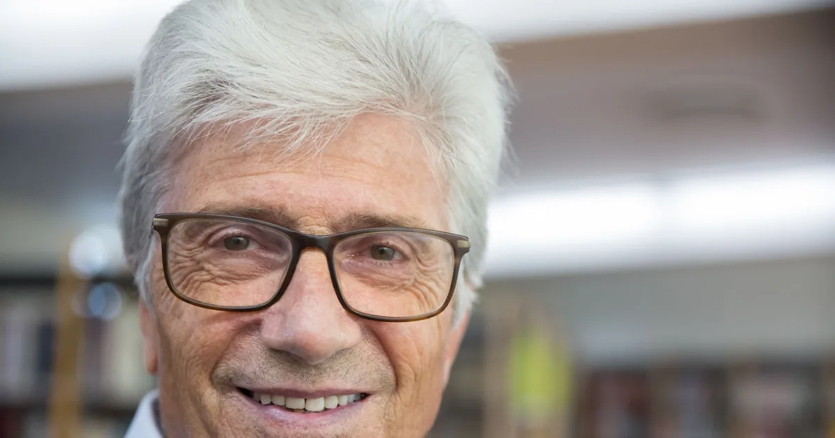 A cheerful senior man with glasses smiling indoors