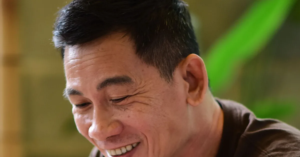 A middle-aged man laughing while relaxing at home