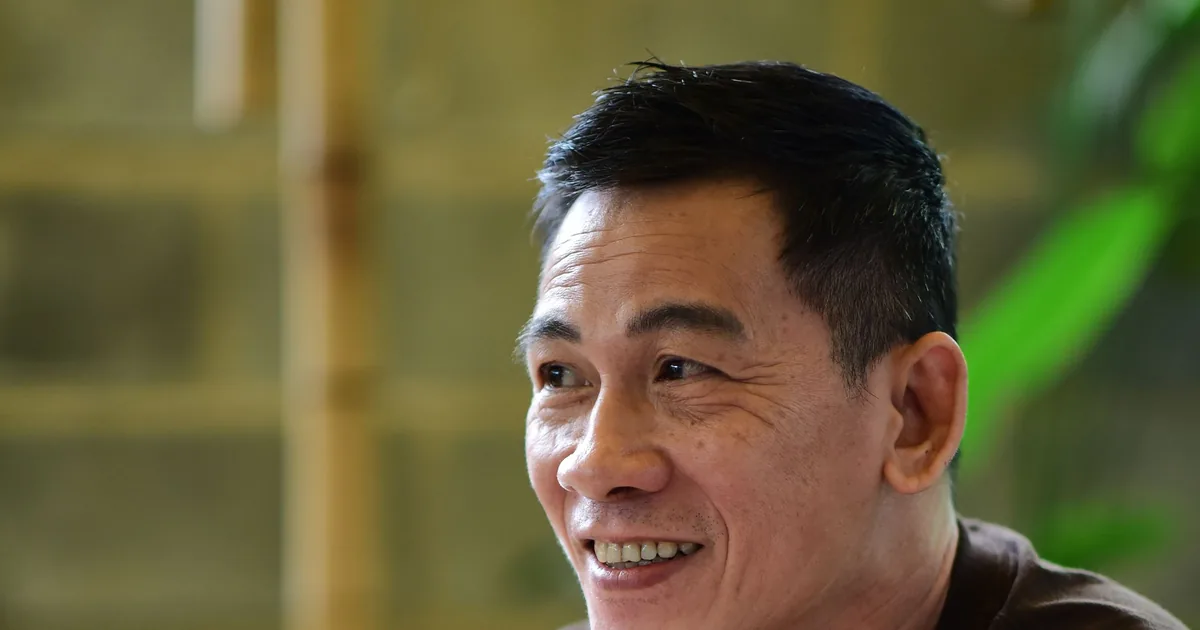 A smiling Asian man relaxing in a cafe with his phone