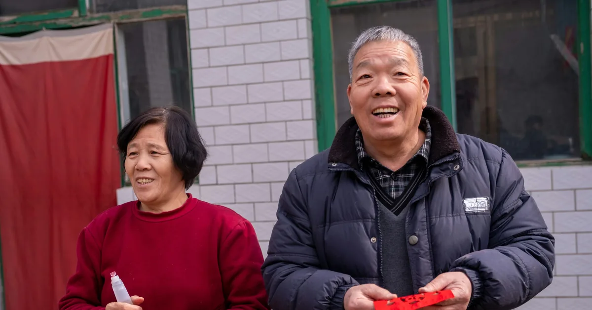 A cheerful elderly Asian couple smiling in a courtyard