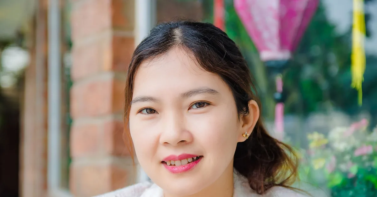A smiling young woman outdoors in warm natural light