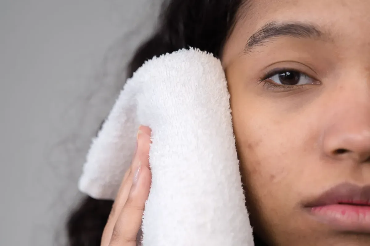 A woman holding a soft warm towel against the side of her face