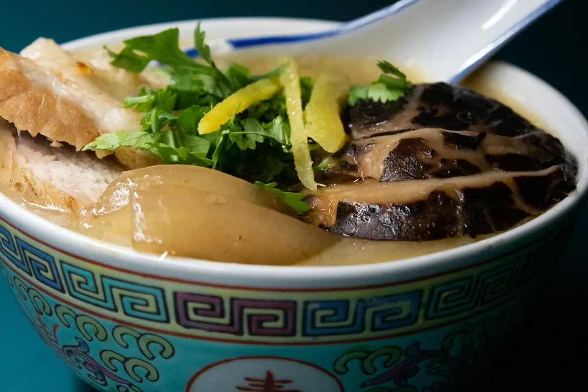 A bowl of rice porridge with mushroom, ginger and herbs, an example of soft food that is easy to eat while a tooth is loose