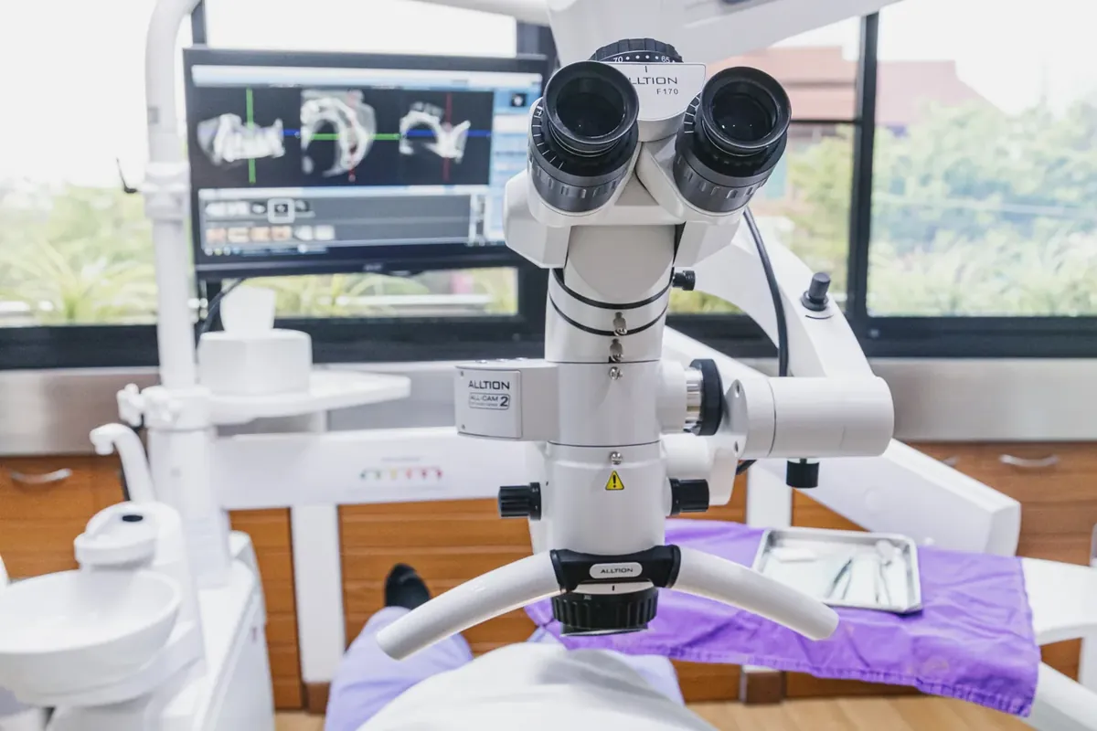A dental operating microscope positioned over a patient in the dental chair