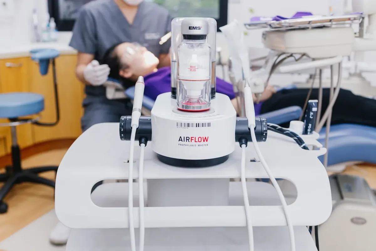 The AIRFLOW unit at Kitcha Dental Clinic with a dentist cleaning a patientss teeth behind it