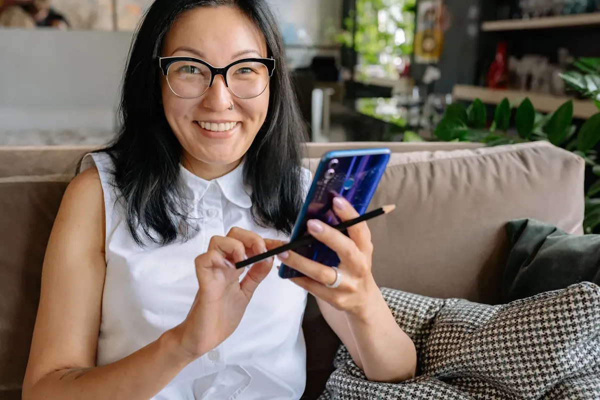 A smiling woman with glasses checking information on her phone at home
