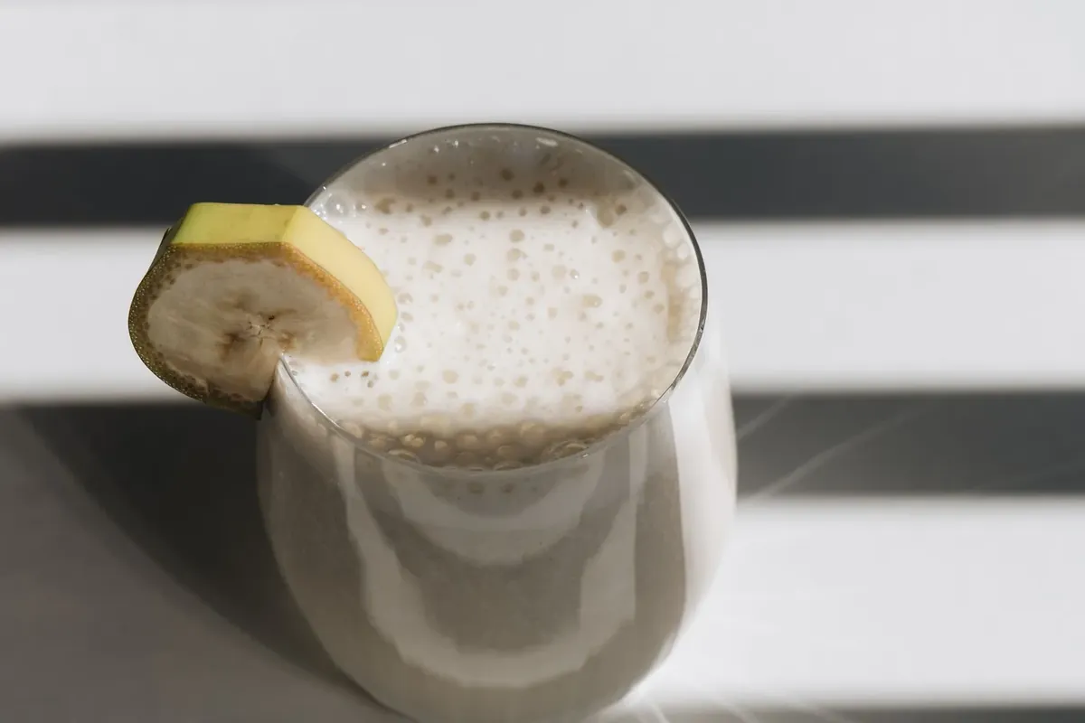 A glass of smooth banana smoothie with no straw, a soft food after wisdom tooth removal