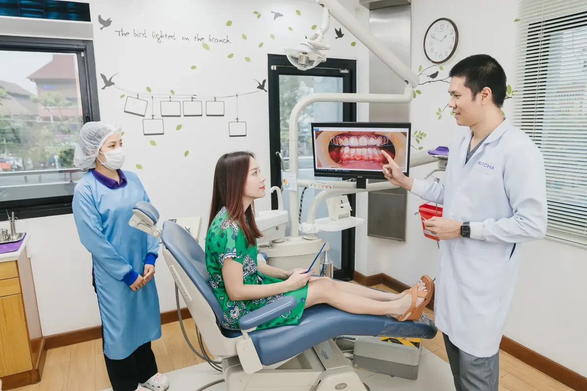 A dentist and assistant reviewing a smile photo on screen with a smiling patient in the dental chair
